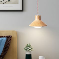 a wooden lamp hanging over a bed next to a vase with a plant in it