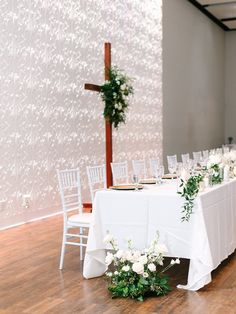 the table is set up with white flowers and greenery for an elegant wedding reception