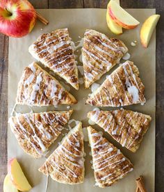 sliced apple pies with cinnamon glaze and apples around them on a piece of parchment paper