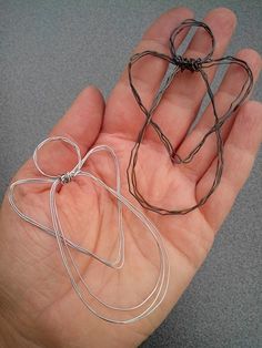 a hand holding two pieces of silver wire