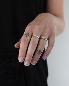 a person wearing a gold ring with an arrow tattoo on their left hand and the other hand has a small star in it