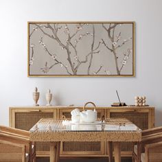 a dining room table and chairs in front of a wall with a painting on it