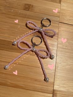 a pair of scissors sitting on top of a wooden floor next to beads and hearts