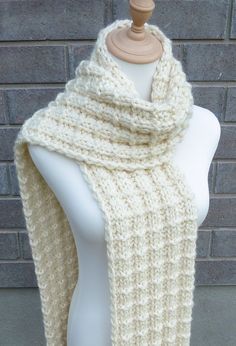 a white knitted scarf sitting on top of a mannequin