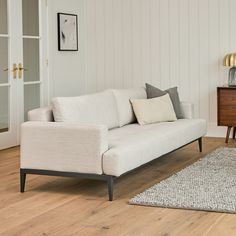 a white couch sitting on top of a hard wood floor next to a wooden table