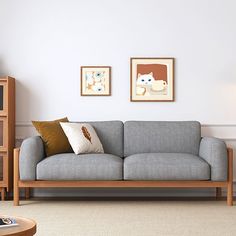 a living room with two framed pictures on the wall and a gray couch in front of it