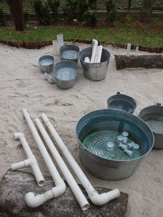 several buckets filled with water sitting on top of a sandy ground