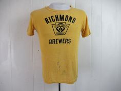 "Vintage 1960s yellow cotton t shirt with black graphics: Richmond Brewers Little League Baseball. Made by Southern Athletic. Size small. Actual measurements are: 38\" around the chest 38\" around the waist 17.5\" shoulder seam to shoulder seam 23\" overall length In \"wrecked\" condition with several holes." Vintage Fitted T-shirt With Letter Print, Fitted Yellow T-shirt With Screen Print, Fitted Yellow T-shirt With Graphic Print, Vintage Cotton T-shirt With Vintage Print, Vintage Yellow Tops With Screen Print, Vintage Yellow Top With Screen Print, Vintage Fitted Short Sleeve T-shirt, 1970s Vintage Print Cotton Tops, 1970s Cotton Vintage Print Tops