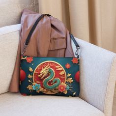 🐉Keep your style on point and your hands free with our Women's Versatile Crossbody Bag/Purse with a Gold, Teal & Red Mystical Dragon Design. It's made of premium faux leather and features dark gray hardware. Thanks to the zip-top closure and multiple inside pockets, you can keep your essentials secure and organized. Transform this crossbody bag with removable wrist and shoulder straps to style it for day-to-night looks. * Outer fabric: faux leather  * Lining: 100% polyester * 11″ × 8″ × 1.5″ (27.9 cm × 20.3 cm × 3.8 cm) * Dark gray hardware * Zip-top closure * Inside zip and slip pockets * Adjustable, removable wrist and shoulder straps * Strap drop length: 14″- 27″ Red Handheld Portable Shoulder Bag, Red Portable Handheld Shoulder Bag, Red Portable Bag For Daily Use, Handheld Mobile Phone Bag As Gift, Red Shoulder Bag With Mobile Phone Holder As Gift, Handheld Bags As Gifts, Handheld Shoulder Bag With Removable Pouch As Gift, Handheld Portable Bags As Gifts, Portable Handheld Bags For Gifts