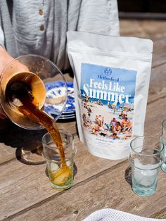 a person pouring tea into glasses on a picnic table