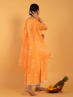 Set of 3 consists of kurta, pants, and dupatta. A summer bright orange kurta enriched with white khari print set on a light cotton base Kurta: Kalidar kurta with white khari print flowers, 3/4th sleeves and contrast white lace detailing on hemline, neckline and sleeves Dupatta: Handspun kota doria dupatta in orange and white, adorned with tassels and khari print Pants: Narrow ivory cotton pants with scallop lace edging. Fit: Relaxed & straight fit Wash Care Instructions: Dry Clean Only Note: Orange Chanderi Salwar Kameez With Printed Motifs, Navratri Cotton Kurta With Sheer Dupatta, Summer Traditional Wear With Printed Motifs In Mulmul, Orange Anarkali Set With Chikankari Embroidery, Straight Kurta With Sheer Dupatta For Summer, Navratri Orange Anarkali Set With Printed Motifs, Summer Straight Kurta With Sheer Dupatta, Festival Orange Palazzo Set With Straight Kurta, Summer Cotton Palazzo Set With Sheer Dupatta