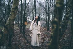 a woman is standing in the woods with her eyes closed and looking up at something