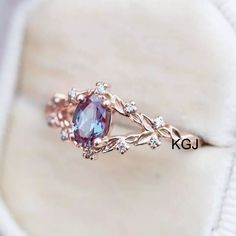 a ring with an oval shaped purple stone surrounded by small white diamonds on a cushion