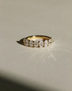 a yellow gold ring with five white diamonds on the top and bottom, sitting on a table