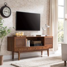 a living room with a large flat screen tv mounted on the wall above a wooden entertainment center