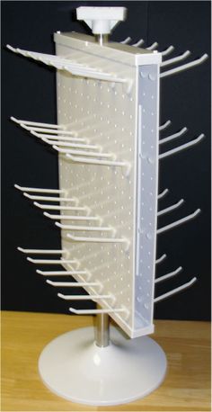 a white rack with several hooks on it sitting on top of a wooden table next to a black wall