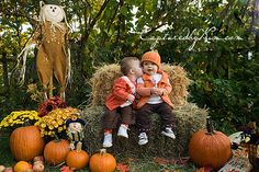 two children sitting on hay bales surrounded by pumpkins