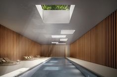 an indoor swimming pool surrounded by wooden slatted walls and flooring with skylights