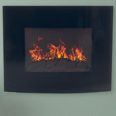 a fire burning inside of a black wall mounted fireplace