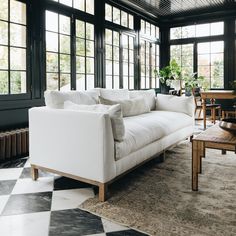 a living room with black and white checkered flooring, large windows, and a couch