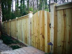 a wooden fence in the middle of a yard with a lamp on top of it