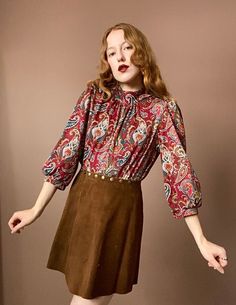 "Vintage 60s Paisley Blouse Gorgeously intricate pattern with burgundy, teal, gold and white details. Mock neck top, buttons up the side of the neck. Slight puff to the shoulders of the blouse. Half length balloon sleeves that end just beneath the elbow. Measurements Shoulders 15\" Bust 40\" Length 24\" Measurements taken with garment laid flat." Fall Retro Blouse With Vintage Print, Retro Vintage Print Blouse For Fall, Retro Blouse With Vintage Print For Fall, Vintage Red Blouse For Fall, Vintage Burgundy Tops For Fall, Vintage Patterned Blouse For Fall, Retro Long Sleeve Tops With Paisley Print, Fall Retro Print Patterned Blouse, Mock Neck Shirt