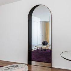 an arched mirror in the middle of a room with a purple rug on the floor