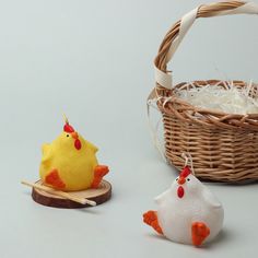 two small stuffed chickens sitting next to a basket