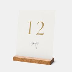 a wooden stand with a white table number and bow tie on it's front