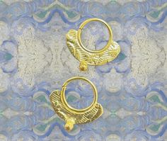 two pairs of gold hoop earrings against a blue and white background