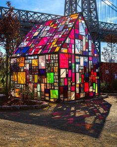 a house made out of stained glass in front of a bridge with the sun shining on it