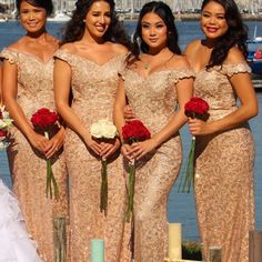 the bridesmaids are posing for a photo in front of the water with their bouquets