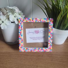 a photo frame sitting on top of a wooden table next to a potted plant