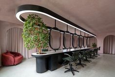 a long table with chairs and a potted plant in the center is surrounded by curved black iron railings