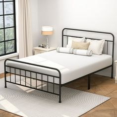 a white bed sitting next to a window on top of a hard wood floored floor