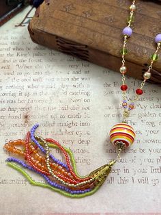 a necklace with beads on it sitting on top of a piece of paper next to a book