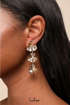 The Lulus Glowing Charm Gold Rhinestone Flower Drop Earrings are ready to capture everyone's attention and get the compliments started! Shiny gold-toned metal shapes these statement-making earrings that feature a series of flowers (with dainty rhinestone details at the centers) that cascade down the drop-style silhouette. Post backs. Earring measures 2. 5" Long. 90% Iron, 10% Stone. Imported. Lulus | Glowing Charm Gold Rhinestone Flower Drop Earrings. Gold Flower Earrings, Flower Drop Earrings, Lulu Fashion, Making Earrings, Rhinestone Flower, Gold Rhinestone, Gold Flower, Accessories Jewelry Earrings, Gold Drop Earrings