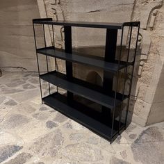 a black shelf sitting on top of a stone floor