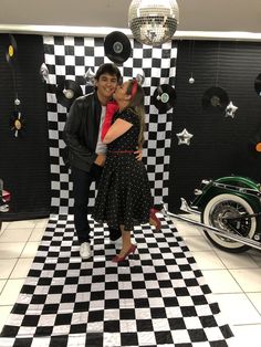 a man and woman standing in front of a black and white checkered floor