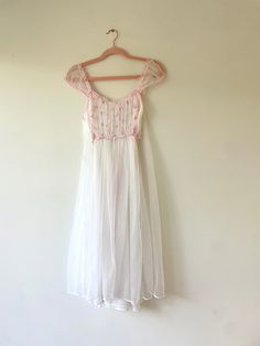 A beautiful and very special mid century style nightgown dress that has been in my family since the late 1950's or early 1960's. A pretty and timeless style that can be worn as lingerie, and also makes the prettiest dress for day or night, for party or brunch, for wedding guest. Perfect for a  bride to be for her bridal trousseau.   Brand: Unknown No Label Condition:  Excellent - No Visible Stains Or Flaws.  Like New Circa:  Late 1950's / Early 60's Size:  XS-Small Color: White/ Pink Layered Sheer Chiffon Over Attached Interior Slip Pink Satin Adjustable Ribbon In Back Under Top Layer Below The Knee Length Pink Lace Overlay At Ruched Bust Ruched Cap Sleeve Approximate Measurements: 34" Bust, 28" Waist, 36" Hip, 41" Long" From Top Of Shoulder To Bottom Hemline Dress up with a cute kitten he Vintage Nightgown For Wedding Night, Vintage White Nightgown For Wedding Night, Vintage Sheer Nightgown For Summer, Vintage Sheer Nightgown For Wedding Night, Vintage Lace Trim Nightgown For Spring, Vintage Summer Sleepwear, Vintage Summer Wedding Night Dress, Vintage Sheer Dresses For Bedtime, Vintage Sheer Nightgown For Sleep