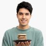 a man holding a plate with a hamburger on it