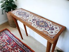 a wooden table sitting on top of a rug next to a plant