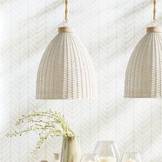 two lamps hanging over a table with wine glasses and vases