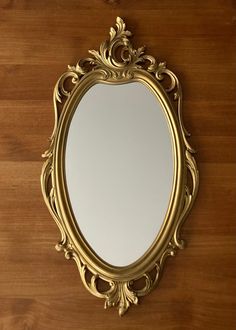 an ornate gold framed mirror hanging on a wooden door with wood flooring and walls