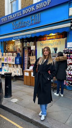 a woman standing on the sidewalk in front of a book shop