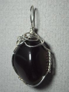 Apache Tear Pendant Wire Wrapped in .925 Sterling Silver Round Wire This beautiful stone, originated from a volcanic eruption, is of a relatively consistent translucent light smoky grey-brown color, yet still appears black in reflected light, against most backgrounds. It wears well with almost any color of clothing, as it compliments either grey or brown based color tones. An exception might be black, since this stone will appear black on black. Consistent color and near flawless appearance make Elegant Obsidian Jewelry For Healing, Classic Smoky Quartz Jewelry As Gift, Classic Smoky Quartz Jewelry As A Gift, Formal Silver Smoky Quartz Jewelry, Silver Obsidian Jewelry For Healing, Apache Tears, Volcanic Eruption, Reflected Light, Color Tones