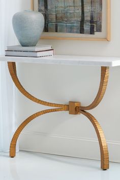 a table with a vase on top of it next to a book and a painting