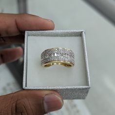 a person holding up a ring in a box with diamonds on the inside and outside