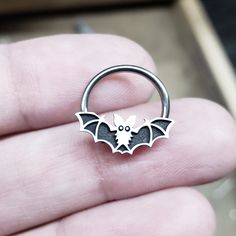 IMPORTANT (size & measuring guide): https://metallotus.com/blogs/body-jewelry/how-to-measure-your-piercing This 16 gauge niobium captive bead ring features a silver bat captive bead design that measures approximately 14.5mm (wide) x 6mm (tall). It works well for septum, conch, helix and daith piercings. * The bat bead design will take up approximately 3mm of the inner diameter when worn as septum or daith jewelry. * Each bead is carefully antiqued and then given a hand-brushed finish to high Cute Septum Rings, Daith Piercings, Captive Bead Ring, Conch Piercings, Daith Jewelry, Halloween Bat, Daith Piercing, Conch Piercing, Nose Ring Stud