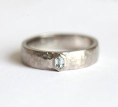 a close up of a wedding ring on a white surface with a diamond in the center